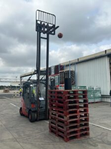 Photo d'un chario logistique essayant de faire un panier de basket avec un ballon et des palettes 